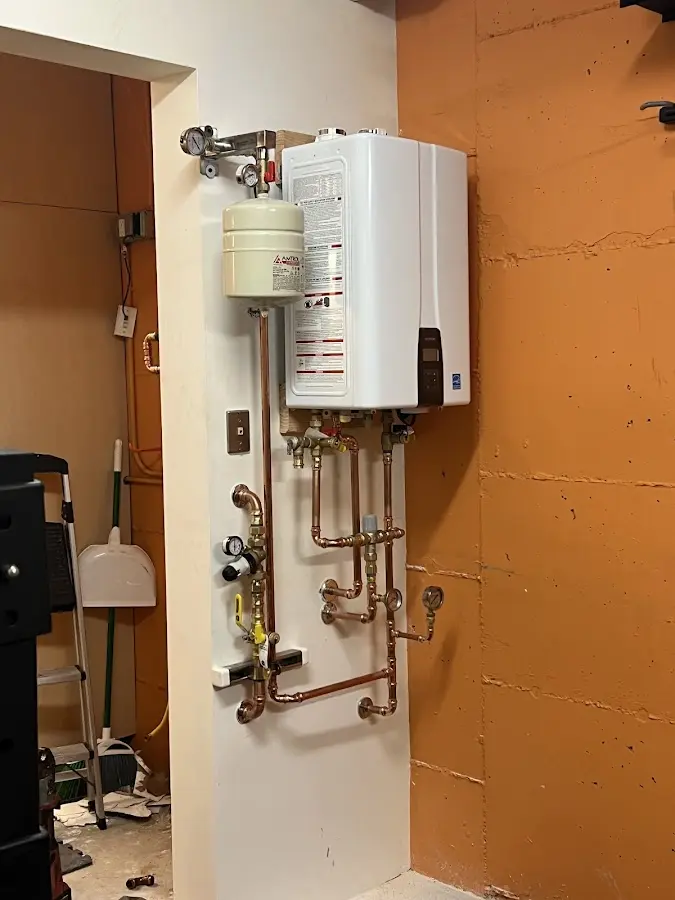 Plumbing technician inspecting water heater connections in Little Falls